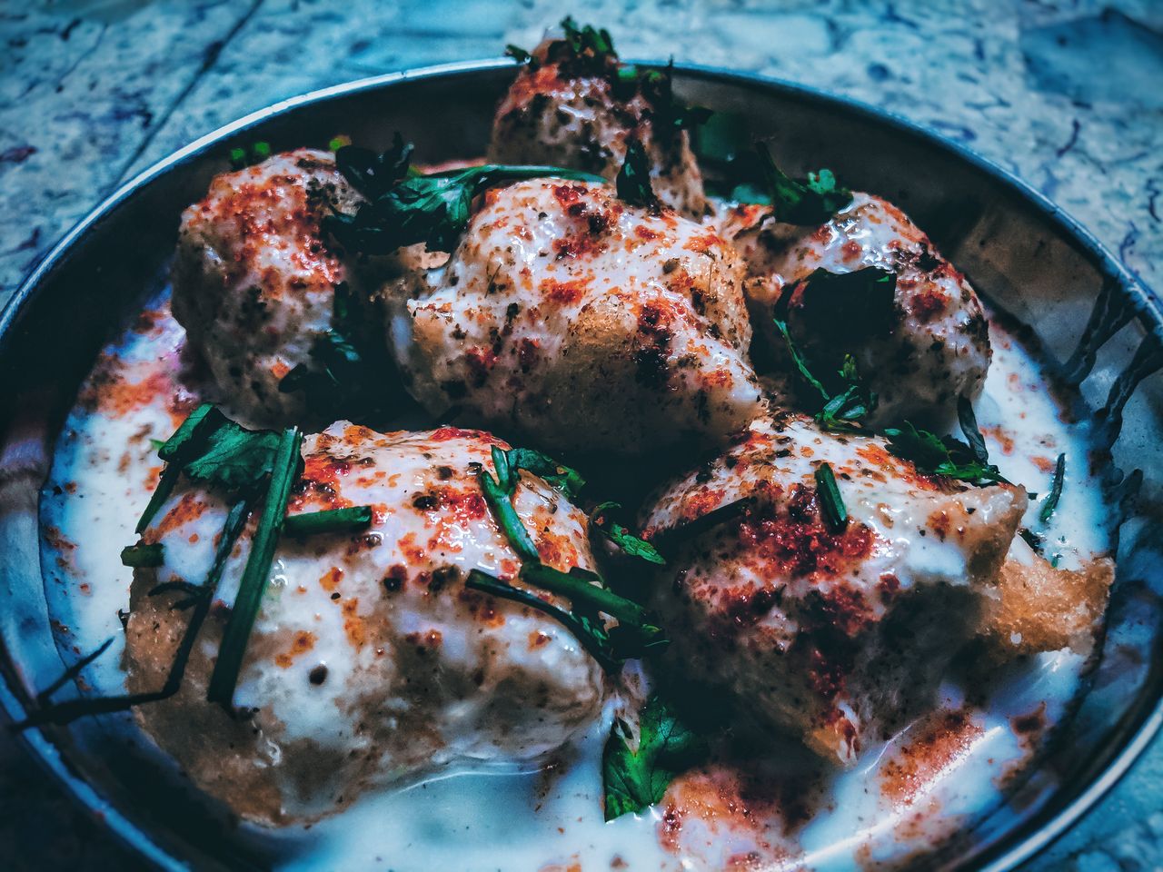 services-02 Close-up of traditional Indian dahi vada garnished with yogurt, herbs, and spices.