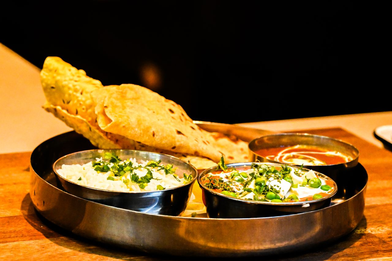 team-02 Exquisite Indian thali with naan bread, paneer curry, and aromatic rice served on a wooden table.